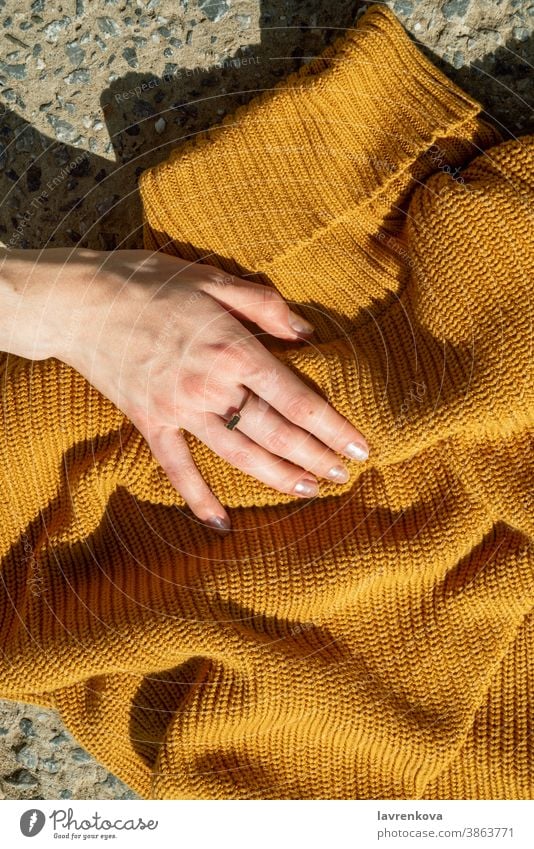 Top view of female hands touching on mustard yellow knit sweater on stone background girl knitted noface faceless stylish urban autumn detail woolen fashion