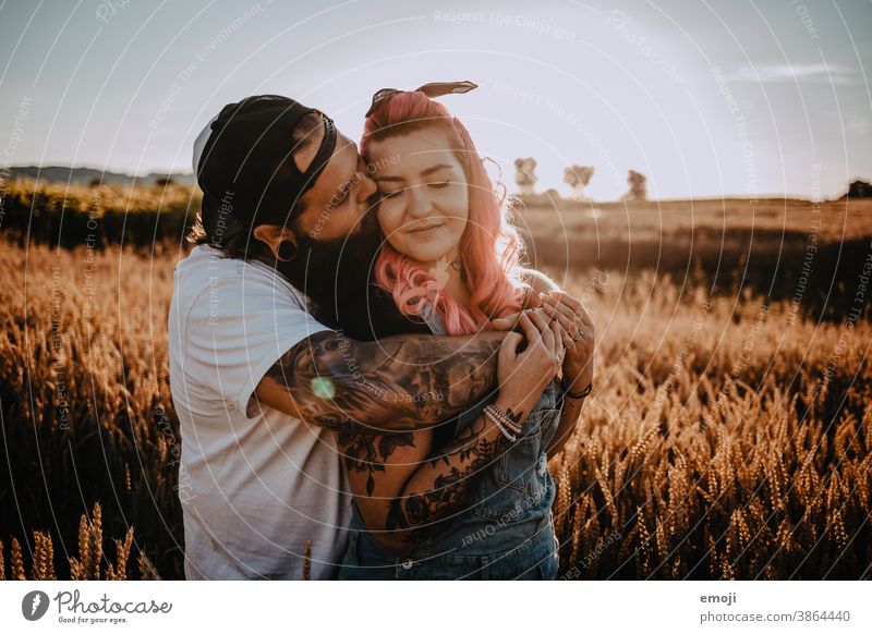 Couple with tattoos and pink hair kiss Woman Man Hipster Hip & trendy Cuddling heartfelt Tattoo Cornfield Field out Love In love hug Sunset teen proximity