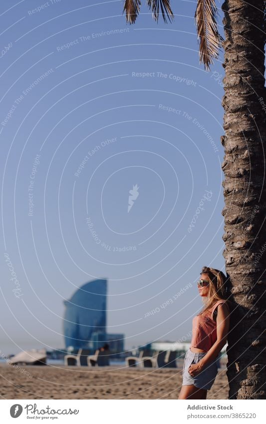 Woman relaxing near palm tree in city woman enjoy stroll weekend carefree summer female tropical exotic sunny lean holiday young urban peaceful harmony idyllic