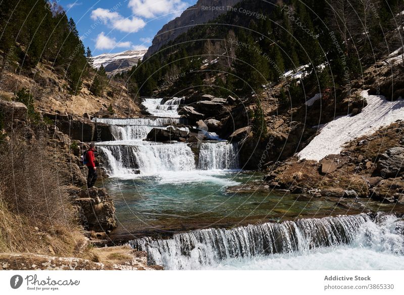 Traveler near cascade waterfall in mountains traveler admire landscape amazing highland terrain scenery pyrenees ordesa valley spain range stream scenic journey