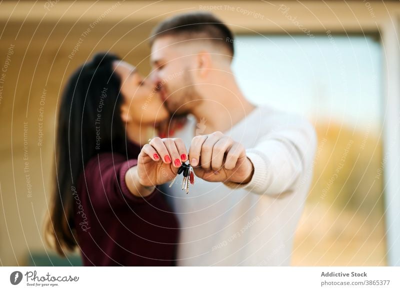 Excited couple with keys from new house real estate kissing excited hug homeowner together embrace smile cheerful relationship property enjoy happy positive