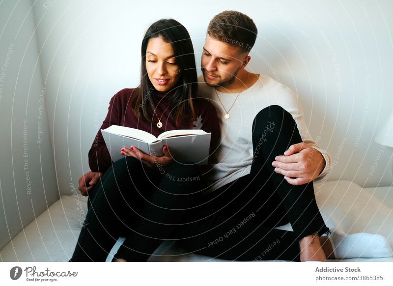 Calm couple reading book on bed together relax literature cuddle bedroom weekend interesting cozy relationship love peaceful romantic sit novel girlfriend