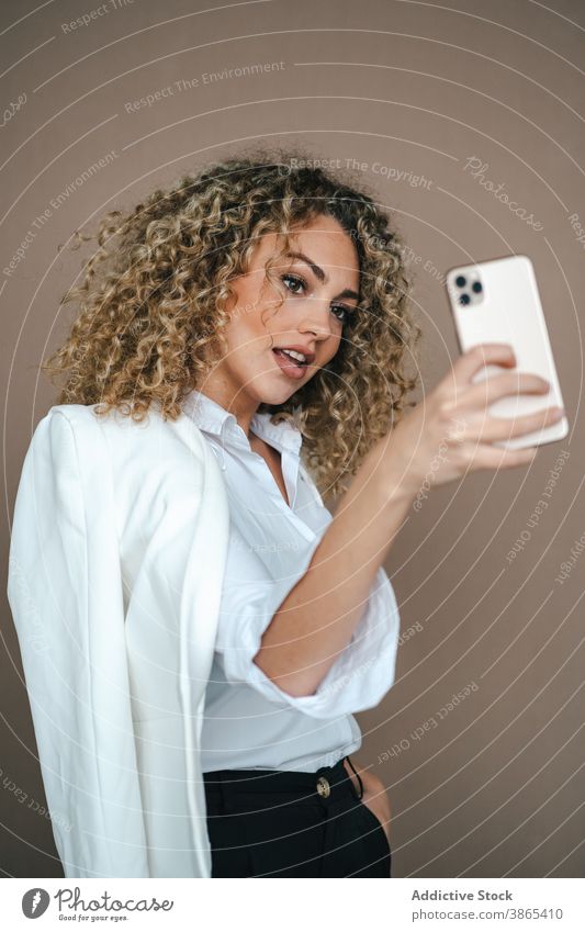 Charming woman taking selfie on smartphone smiling happy self portrait make face lip studio charming female style contemporary trendy gadget device mobile