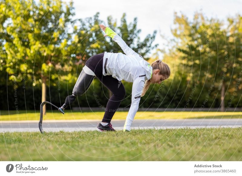 Athletic woman with artificial limb of leg training in park explosive start runner paralympic prosthesis sportswoman female exercise bionic ready prepare