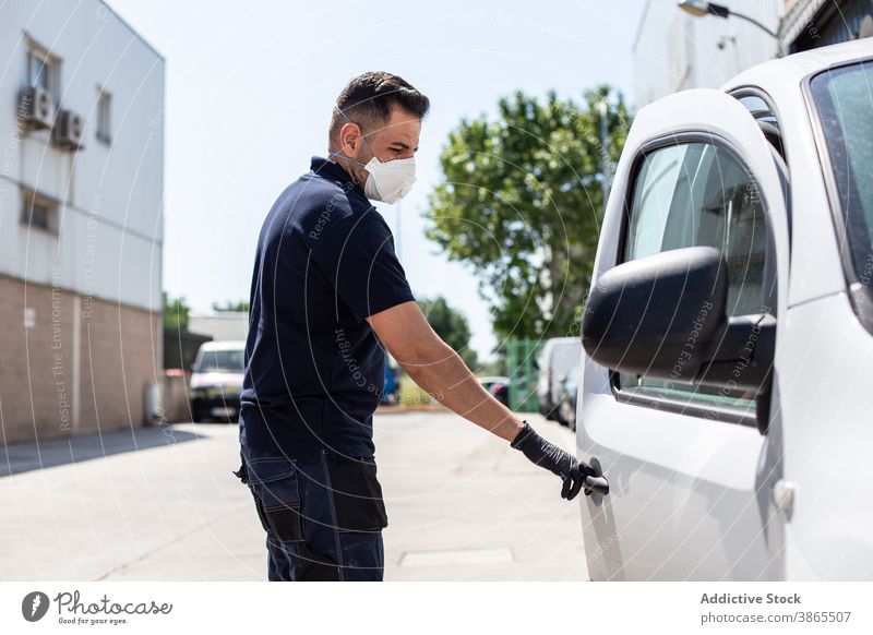 Mechanic in respirator opening car door man street mechanic town modern protect male safety transport city service glove mask technician work job urban