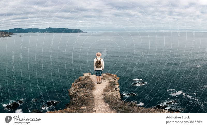 Man standing on hill and enjoying seascape traveler observe viewpoint man explore wanderlust adventure wonderful male scenery rocky mountain cloudy sky nature