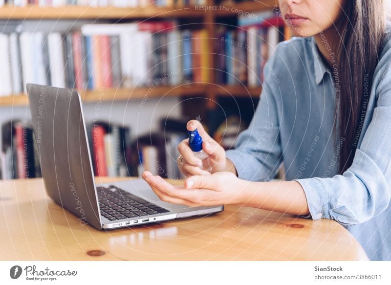 Coronavirus concept. Girl working from home spray antiseptic on her hands for protection from coronavirus. Global call to stay home. covid quarantine spraying