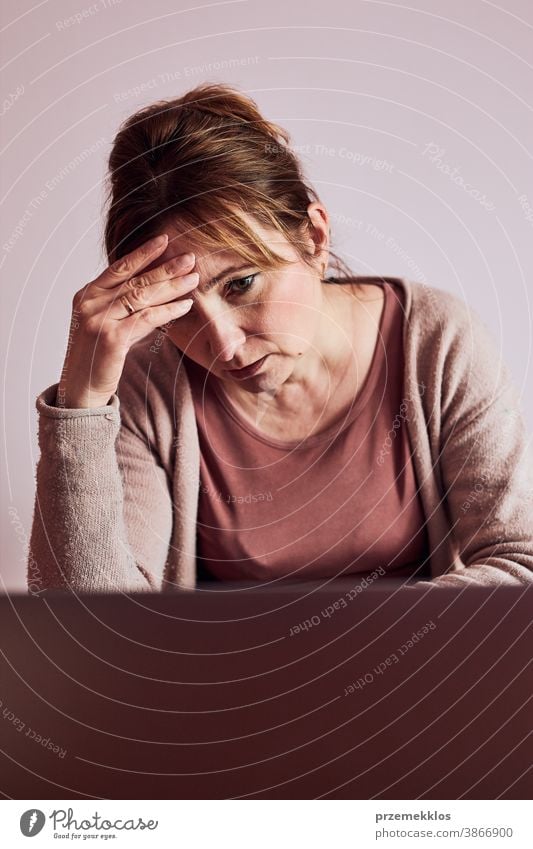 Woman focused on her work working hard doing her job remotely on laptop from home. Woman sitting at desk in front of computer looking at screen. Concept of remote working