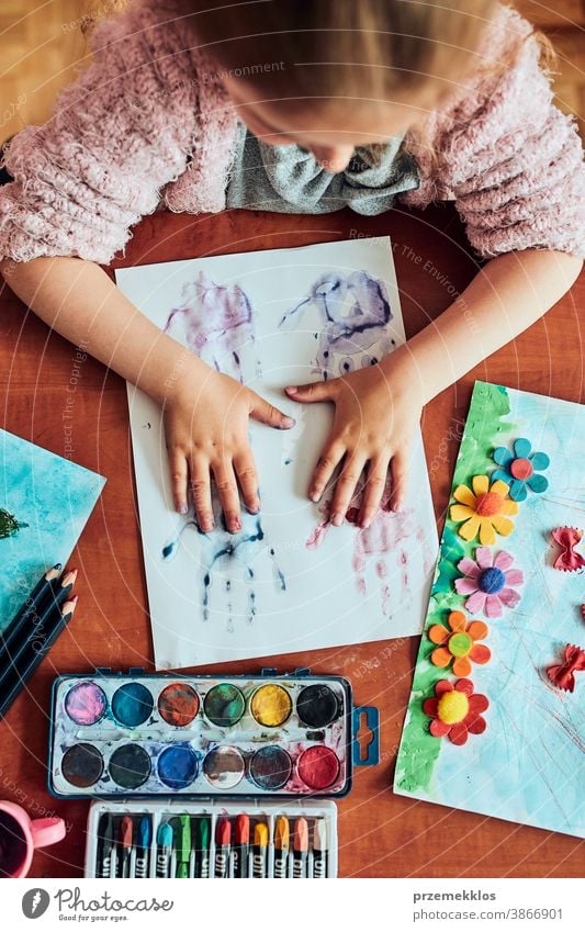 Little girl preschooler painting a picture using colorful paints and crayons. Child having fun making a picture during an art class in the classroom child dye