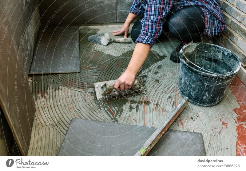 Female mason laying tiles on a terrace unrecognizable woman workman tiling floor hand detail reform imitation cement tile spread tiler glazed terrace working