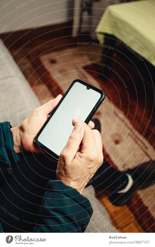 Pair of old hands scrolling over a white screen with copy space phone in a living room person age elderly grandmother mature older retirement senior touch call