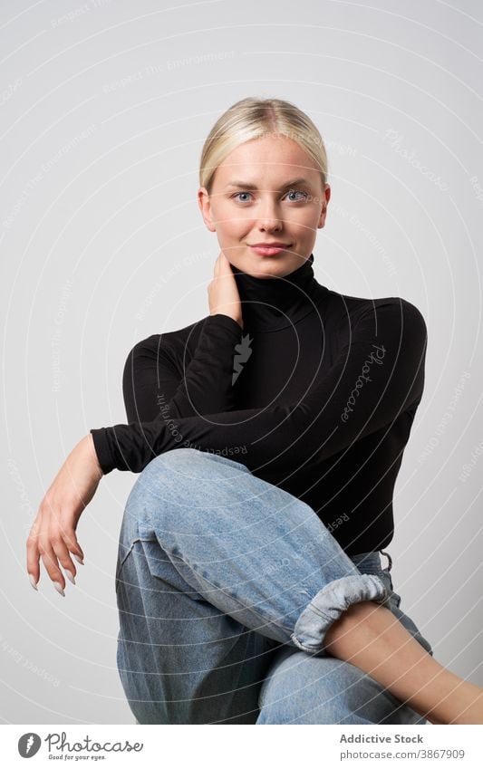 Delighted woman sitting in studio casual style natural beauty female positive young lady legs crossed carefree blonde trendy rest charming expressive pleasant