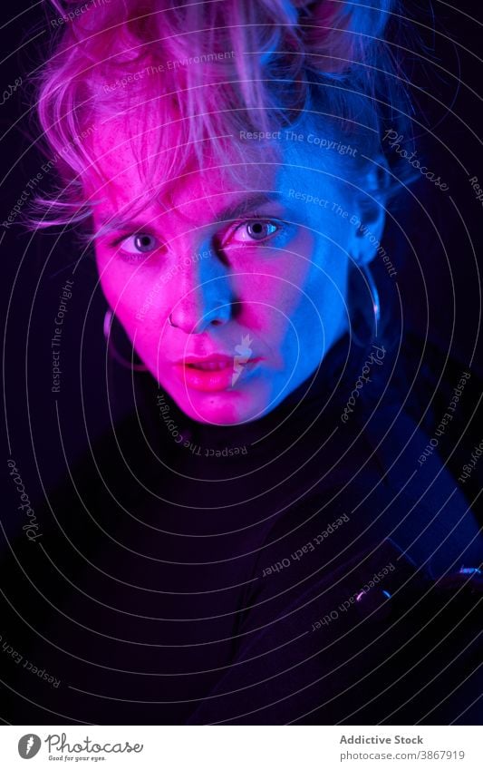 Young woman in neon illumination in darkness confident human face portrait blond serious modern model young female purple illuminate style trendy glow glamour