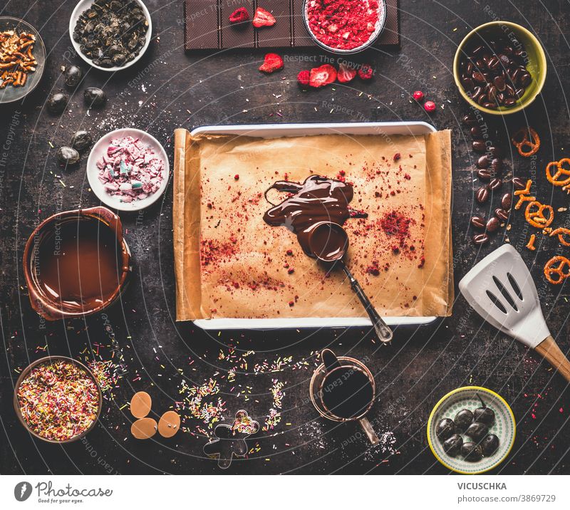 Spoon with melted chocolate on rustic kitchen table with various candies and sweets bar . Top view spoon top view tradition space different group assorted