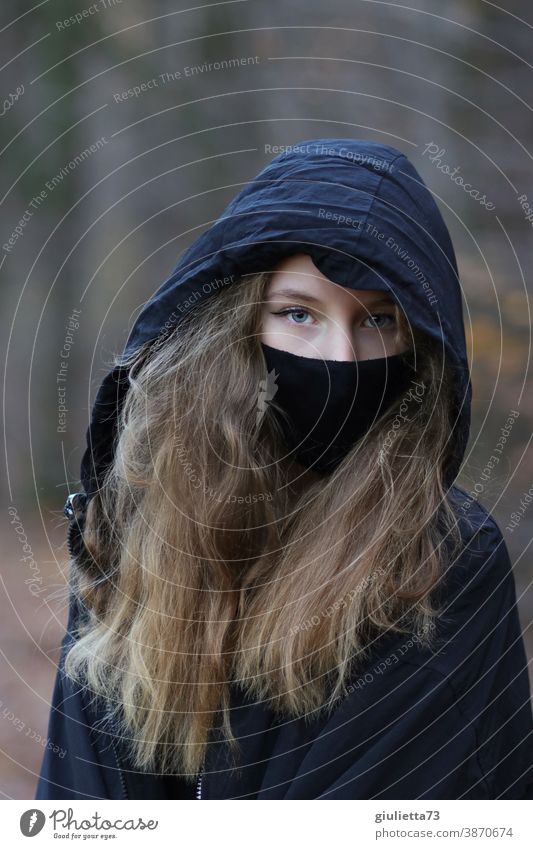 Portrait of a teenage girl in black, with hood and mouth-nose cover/ mask I corona thoughts flu covid-19 somber Epidemic COVID Risk of infection coronavirus