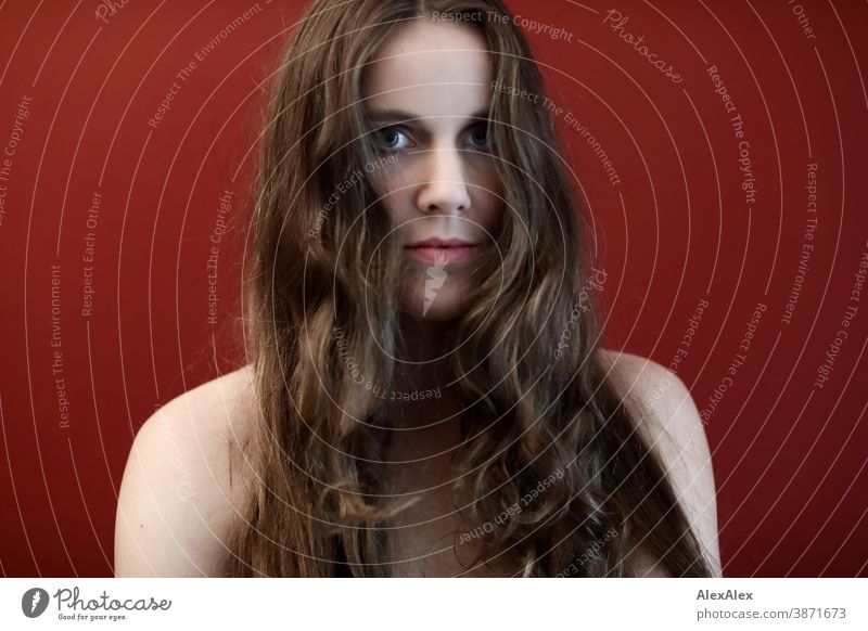 Portrait of a young woman in front of a red wall Woman Slim pretty Brunette long hairs Shoulder Face smart emotionally Skin see look Looking Direct naturally