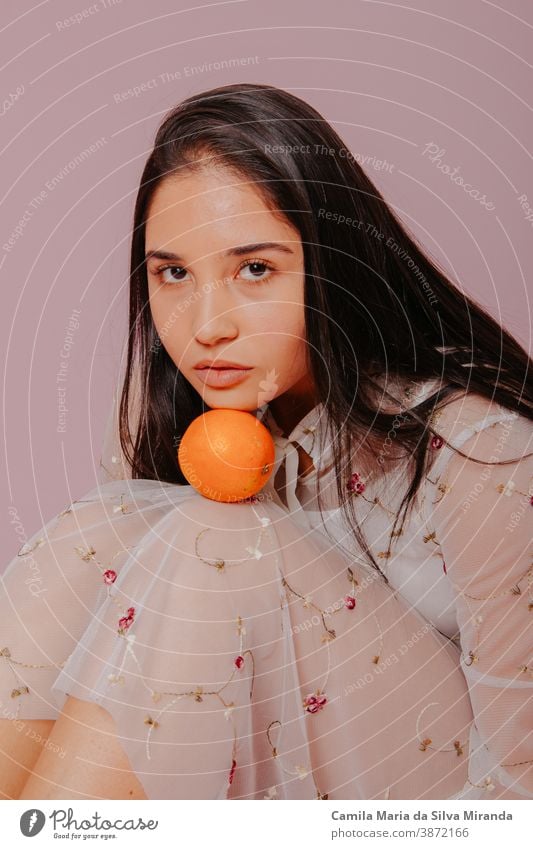 Model holding an orange. Studio shot with pink background. beautiful beauty care citrus closeup cosmetics face fashion fresh fruit girl glamour hair hairstyle