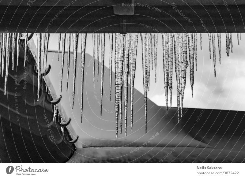 icicles hanging down from the gutter on on a house Beautiful blue bright clear cold cool crystal day drop freeze frost frozen ice icy isolated light melt