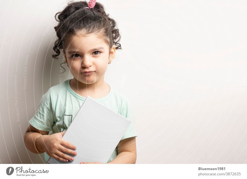 Little girl holding a book with blank cover in front of body mock-up series 268 editable replace little girl body front mockup template paperback thick