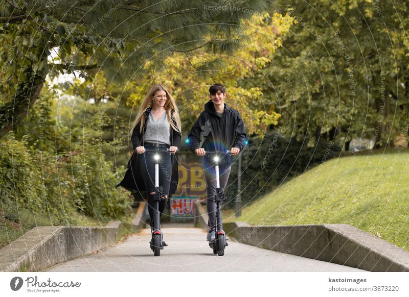 Trendy fashinable teenagers riding public rental electric scooters in urban city environment. New eco-friendly modern public city transport in Ljubljana, Slovenia