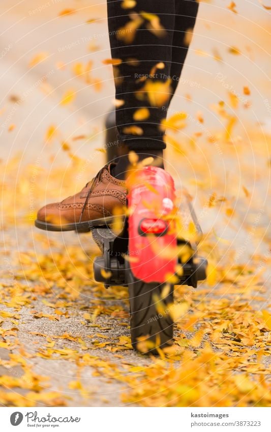 Detail of fashinable hipster girl riding electric scooter in park at fall autumn leaves e-scooter colorful leafs road ride transportation urban man golden light