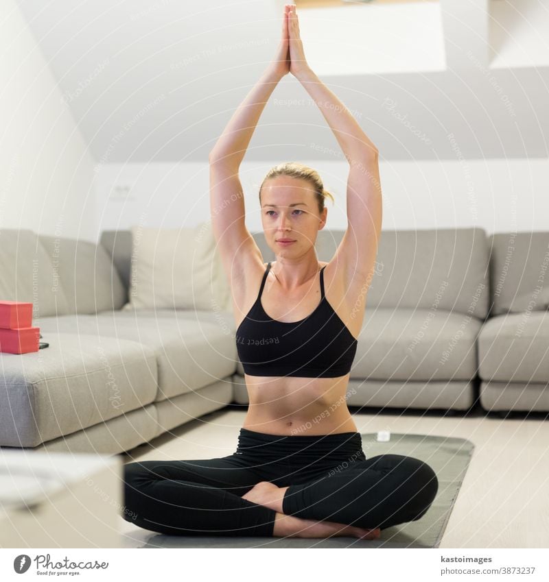 Beautiful blonde woman doing home workout indoors. Woman practice yoga at home. Fit girl using workout tutorials for healthy active lifestyle. Woman using quarantine for home workouts.