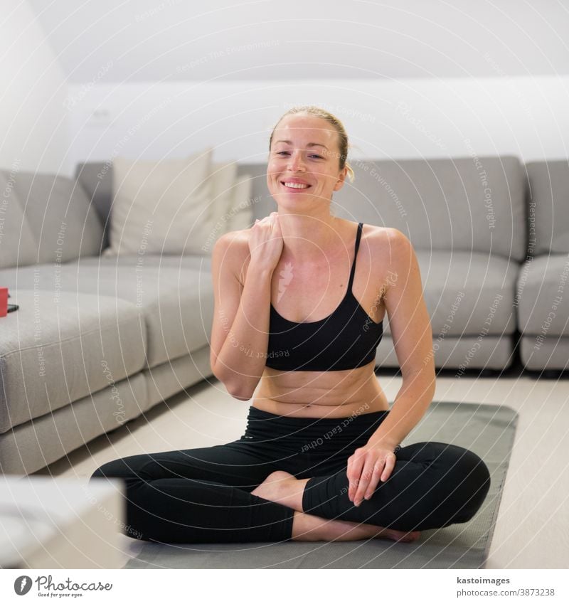 Beautiful blonde woman doing home workout indoors. Woman practice yoga at home. Fit girl using workout tutorials for healthy active lifestyle. Woman using quarantine for home workouts.