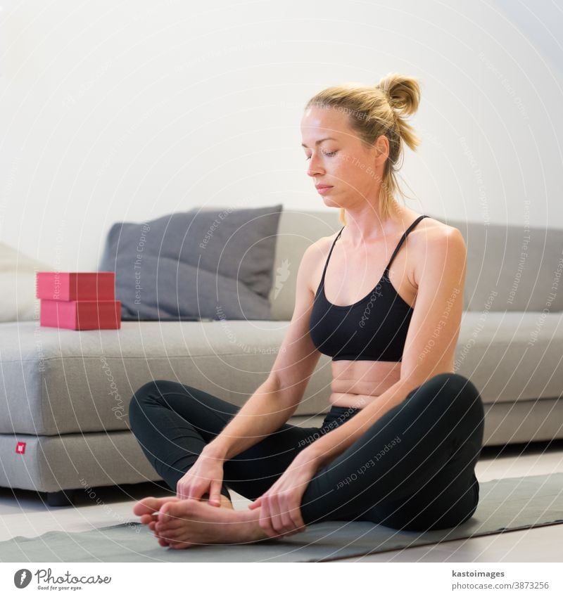 Beautiful blonde woman doing home workout indoors. Woman practice yoga at home. Fit girl using workout tutorials for healthy active lifestyle. Woman using quarantine for home workouts.