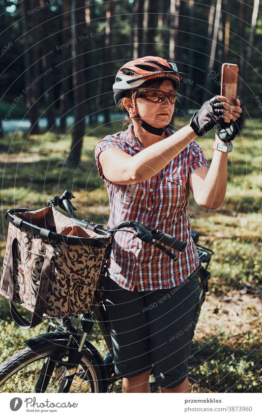 Active woman spending free summer vacation time in a forest on a bicycle trip taking photos using smartphone joy freedom fall recreation adventure enjoy