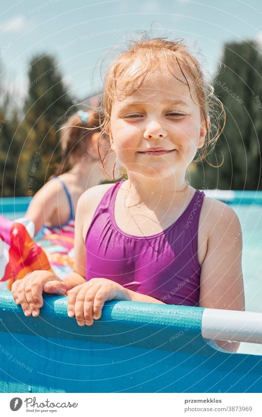 Portrait of happy smiling girl standing in a pool having fun on a summer sunny day authentic backyard childhood children family garden happiness joy kid