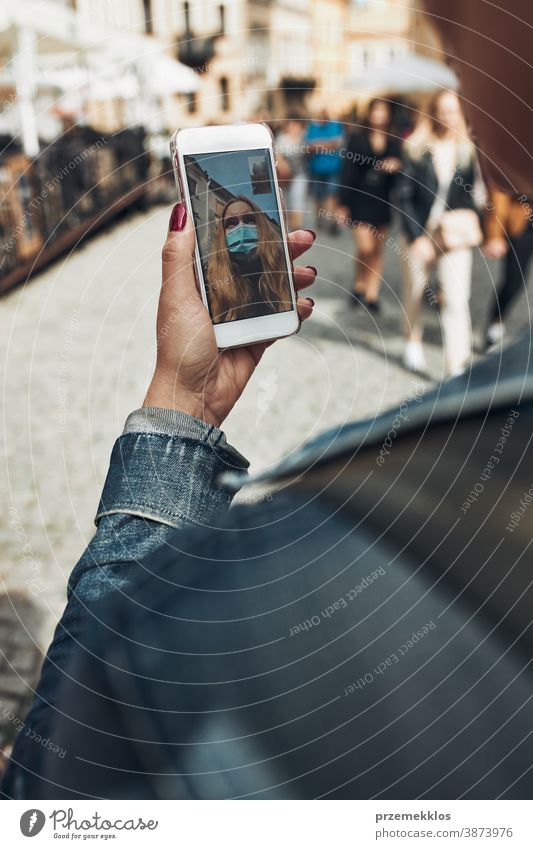 Young woman having video call talking while walking downtown in the evening wearing the face mask to avoid virus infection care caucasian chat contagious corona