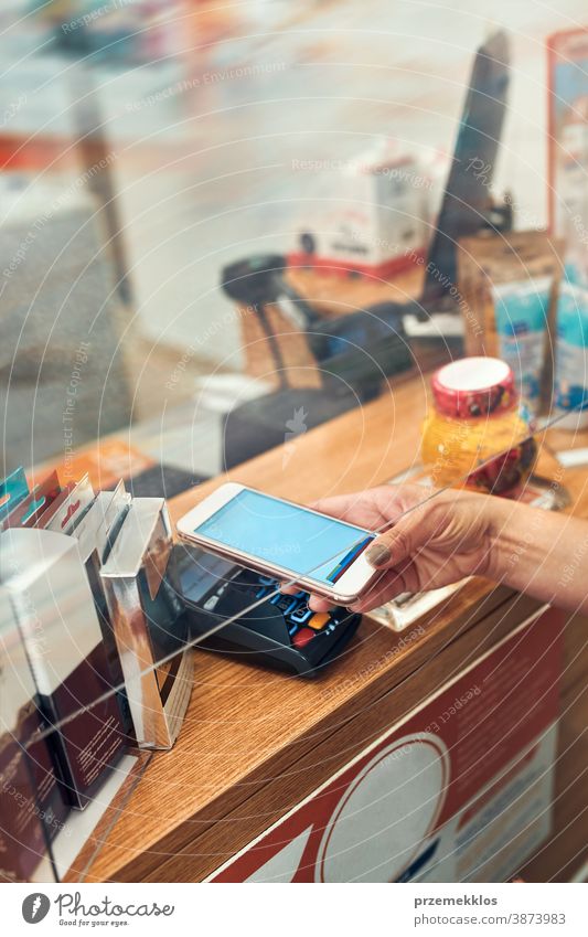 Woman paying for medicines at pharmacy using contactless method of payment via mobile phone woman chemist shop pandemic female care medical drugstore medication