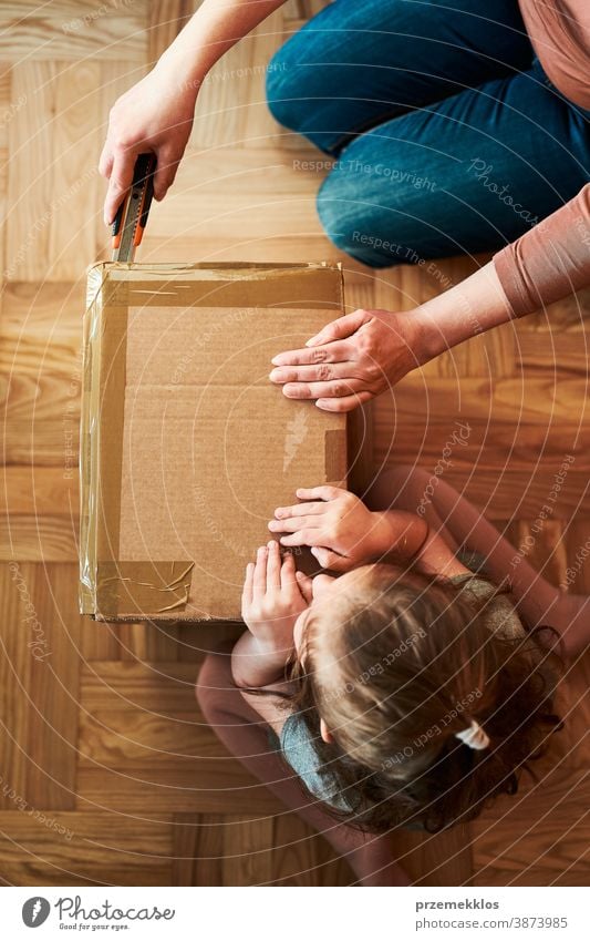 Woman unpacking a cardboard box parcel with help of her daughter view floor gift unboxing tape girl woman filler foam top open home wrapping opening shipping