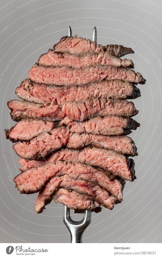 Slices of a steak on a grey background nobody Black Angus Ribeye angus BBQ prime beef Carving fork Impaled Steak steak slices Fork Gray medium Juicy Beef