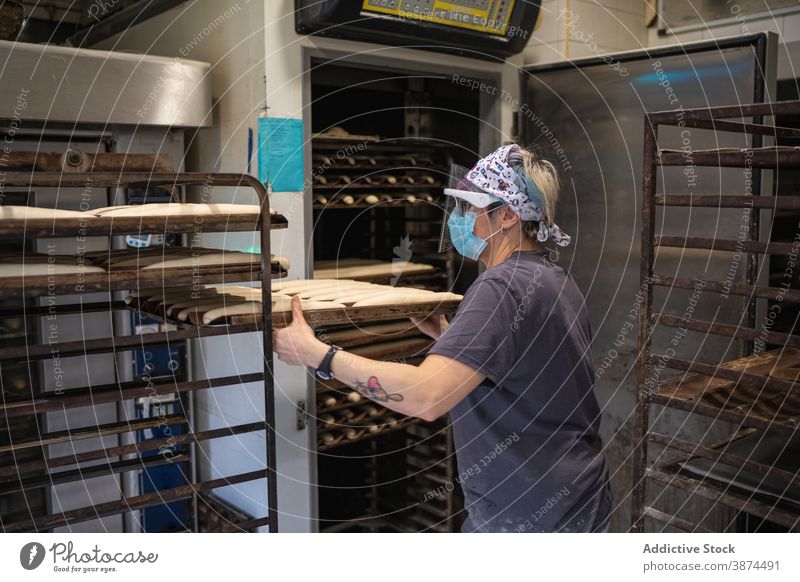 Woman preparing bread in bakery oven woman bakehouse cook baguette baking pan dough female raw mask shield new normal coronavirus hot job occupation recipe chef