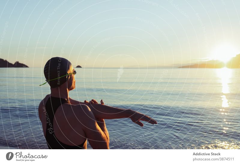 Male swimmer warming up before training warm up stretch man sea seashore beach swimsuit male prepare cap fit workout body healthy active practice activity