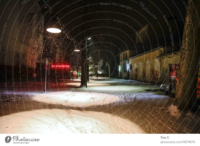 the entrance to the Prater beer garden with restaurant in winter . It is late evening and it is snowing . Berlin Restaurant chestnut avenue Prenzlauer Berg