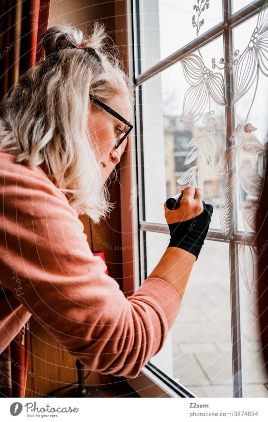 Young woman painting the window panes in an inn Guesthouse decoration dedicate Wood Bavarian interior guest room Restaurant chairs living room tables