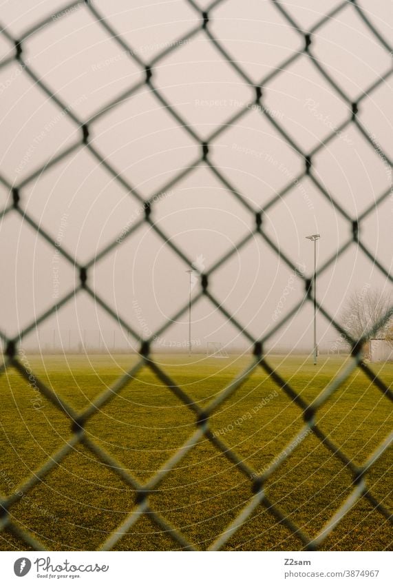 Deserted football field in Corona times Football pitch Foot ball workout Empty Lawn Meadow Green Winter Gray Fog Fence lock down corona coronavirus Sports