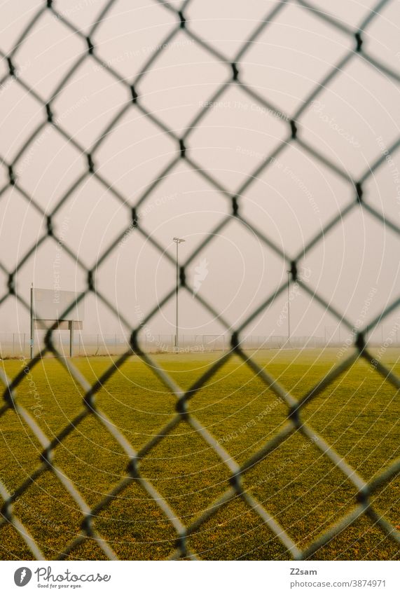 Deserted football field in Corona times Football pitch Foot ball workout Empty Lawn Meadow Green Winter Gray Fog Fence lock down corona coronavirus Sports