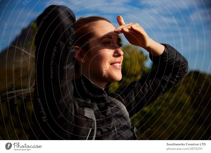 Active Young Woman Hiking In Countryside Shielding Her Eyes From The Sun staycation travelling woman young women hike hiking walk walking trek active backpack