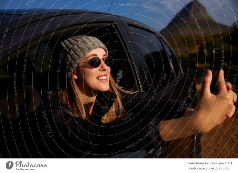 Young Woman On Road Trip Vacation Taking Photo Out Of Rental Car Window On Mobile Phone road trip vacation woman young women holiday car driving driver car hire