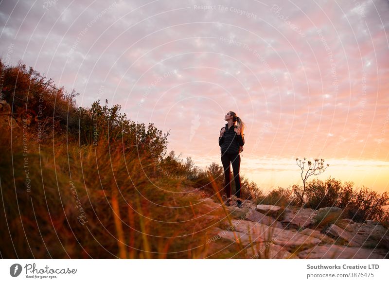 Front View Of Young Woman With Backpack Setting Off For Hike Along Countryside Path At Sunset adventure sunset sunrise woman young women hike hiking walk