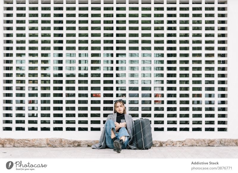 Lost woman with suitcase sitting on the street on street tourist city lost luggage baggage traveler female pavement trip sidewalk vacation holiday young rest