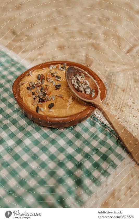 Tasty homemade hummus on table dish mashed chickpea serve vegetarian food healthy food vegan rosemary sprig sunflower seed garnish wooden spoon bowl tasty