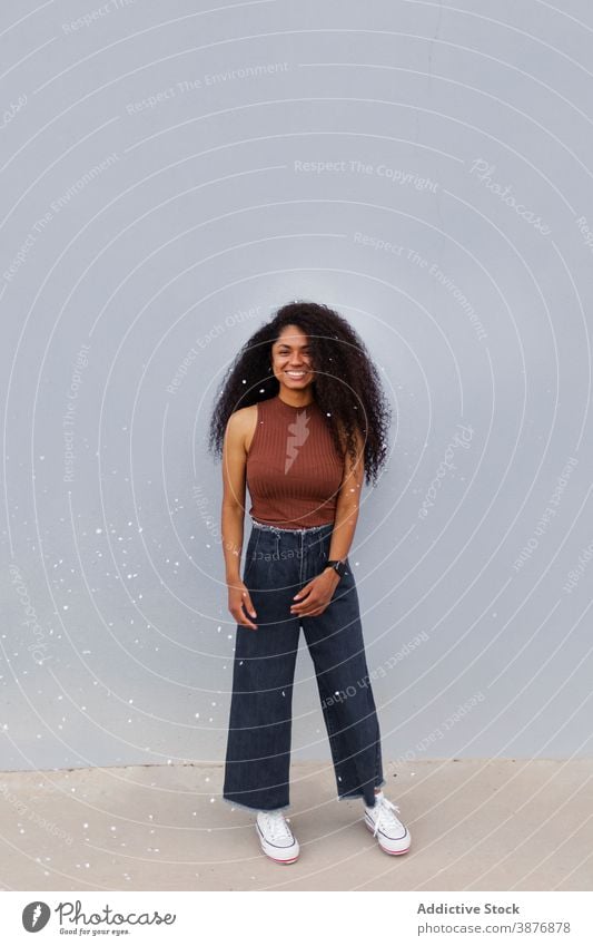 Positive ethnic woman with Afro hairstyle on street fly confetti city festive cheerful joy curly hair afro female black african american modern fun optimist