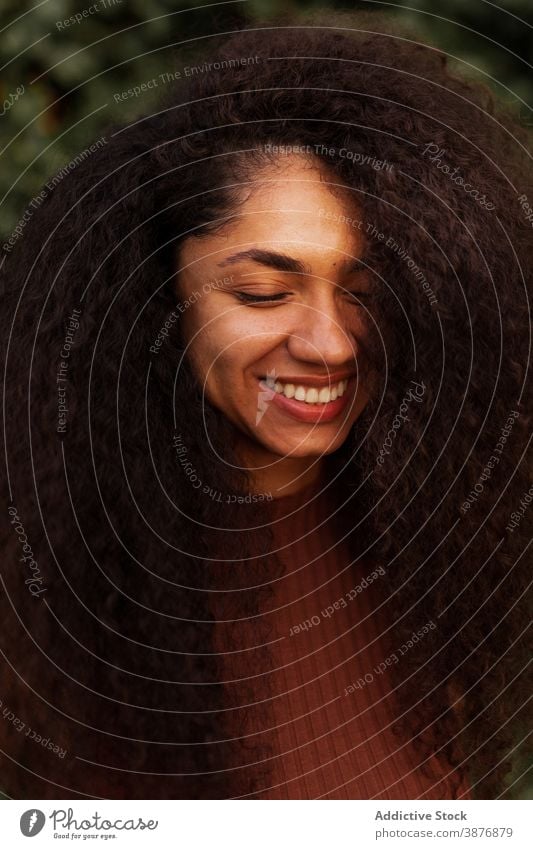 Happy ethnic woman in green garden charming smile natural beauty candid curly hair afro hairstyle park female black african american young happy cheerful joy