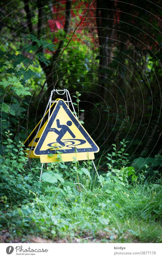 Warning sign for danger of slipping in the open air. bizarre and funny Slippery surface Nature Garden Signs and labeling Warning label Funny Exceptional bushes