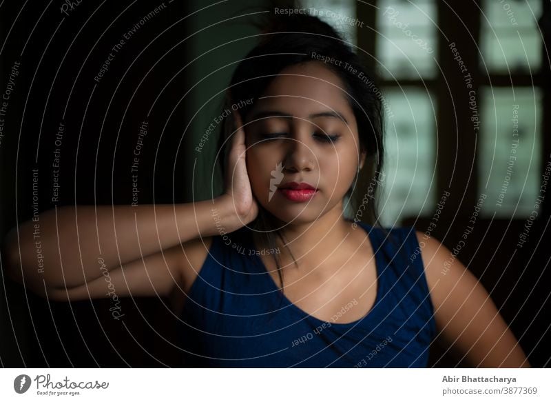 An young and attractive Indian Bengali brunette woman in active wear is doing yoga after waking up in the morning in front of window in her room. Indian lifestyle.