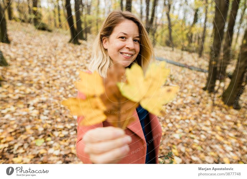 Young woman holding yellow autumn leaves in the forest 30s adult beautiful beauty blonde caucasian cheerful color cute enjoy fall female foliage fresh fun girl